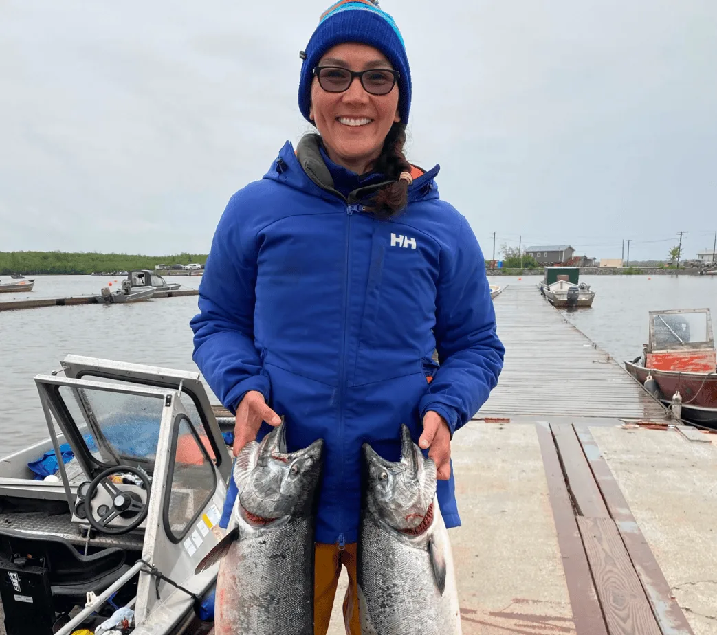 Mary Peltola holding two salmon on a dock.