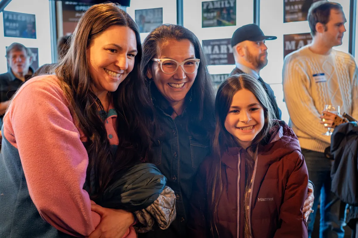 Mary Peltola leans in cheek to cheek with supporters for a photo.