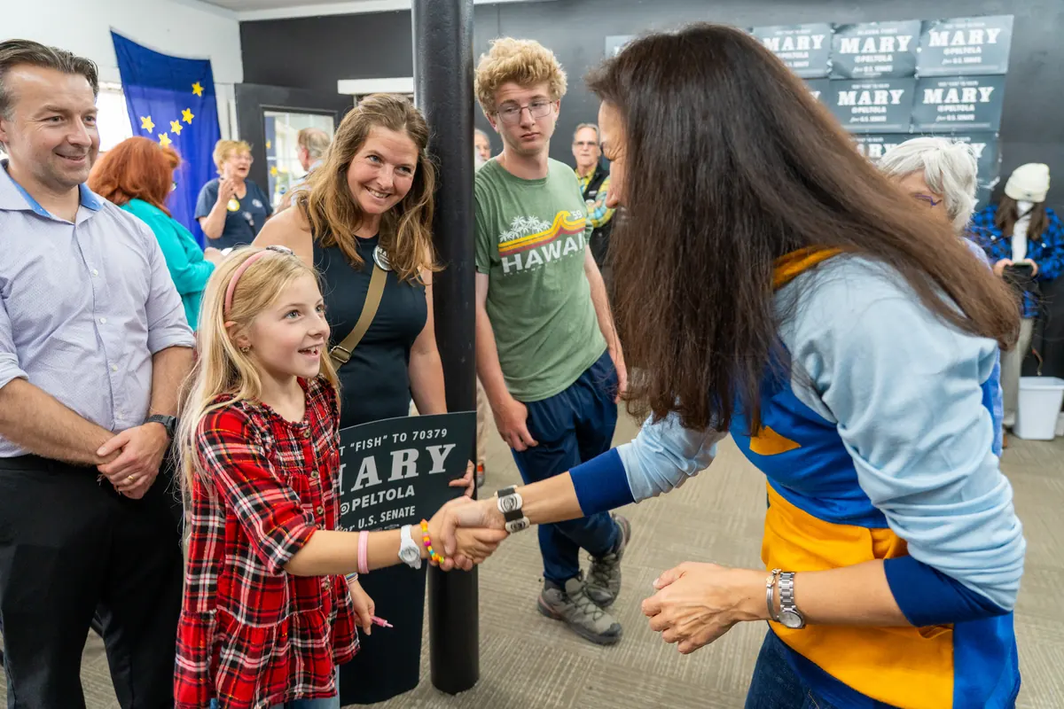 Mary Peltola shakes hands with a young supporter at a campaign event.