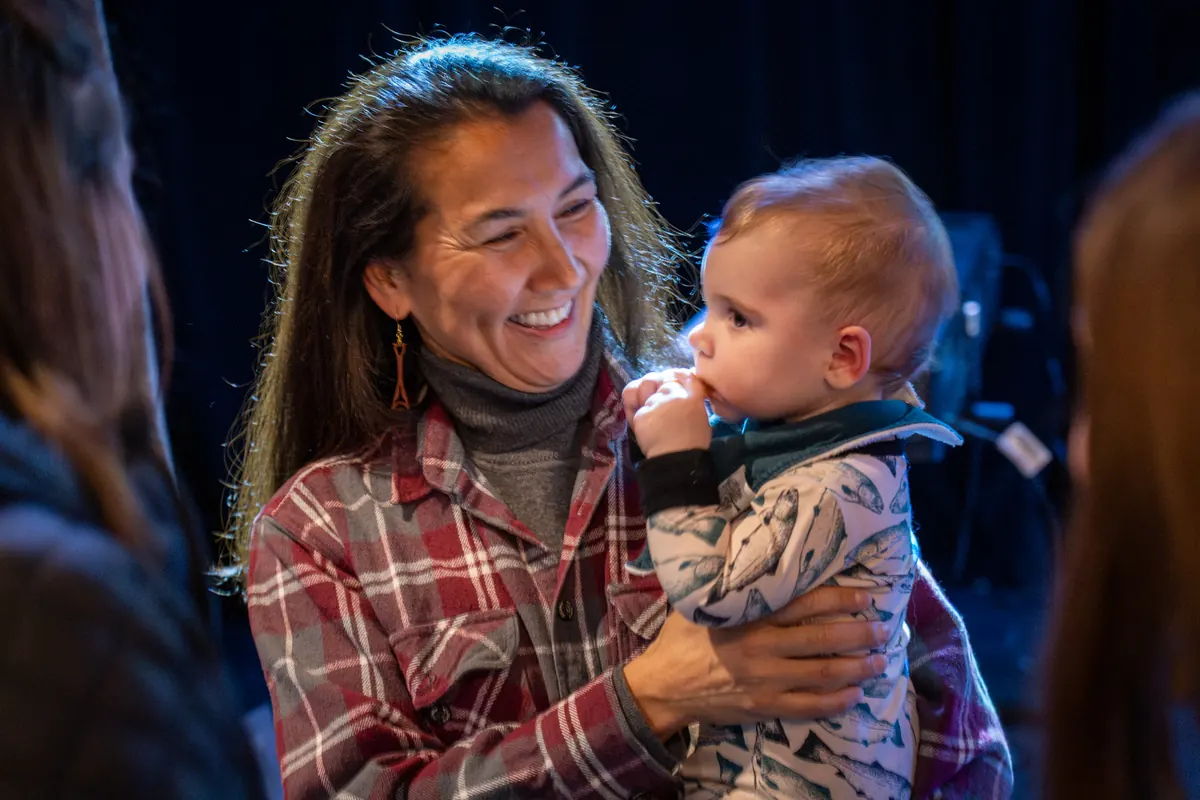 Mary Peltola laughs as she holds a baby at a campaign event.