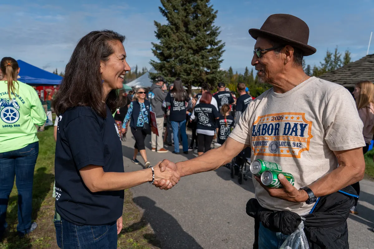 Mary Peltola shakes hands with a union member at a Labor Day picnic.