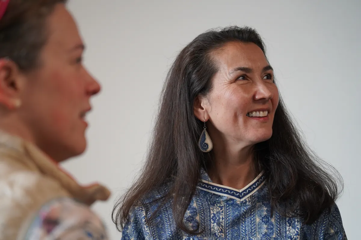 Mary Peltola, in a kuspuk, smiles and looks up.