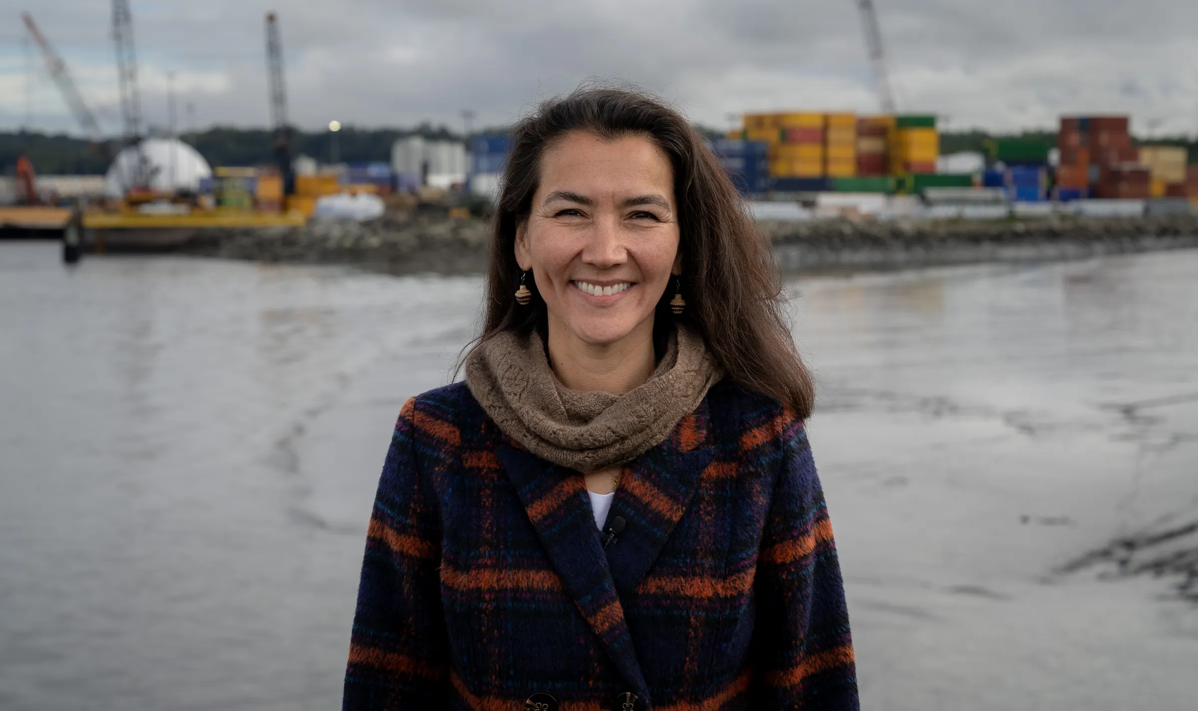 Mary Peltola on the Anchorage waterfront, shipping containers and cranes behind her.