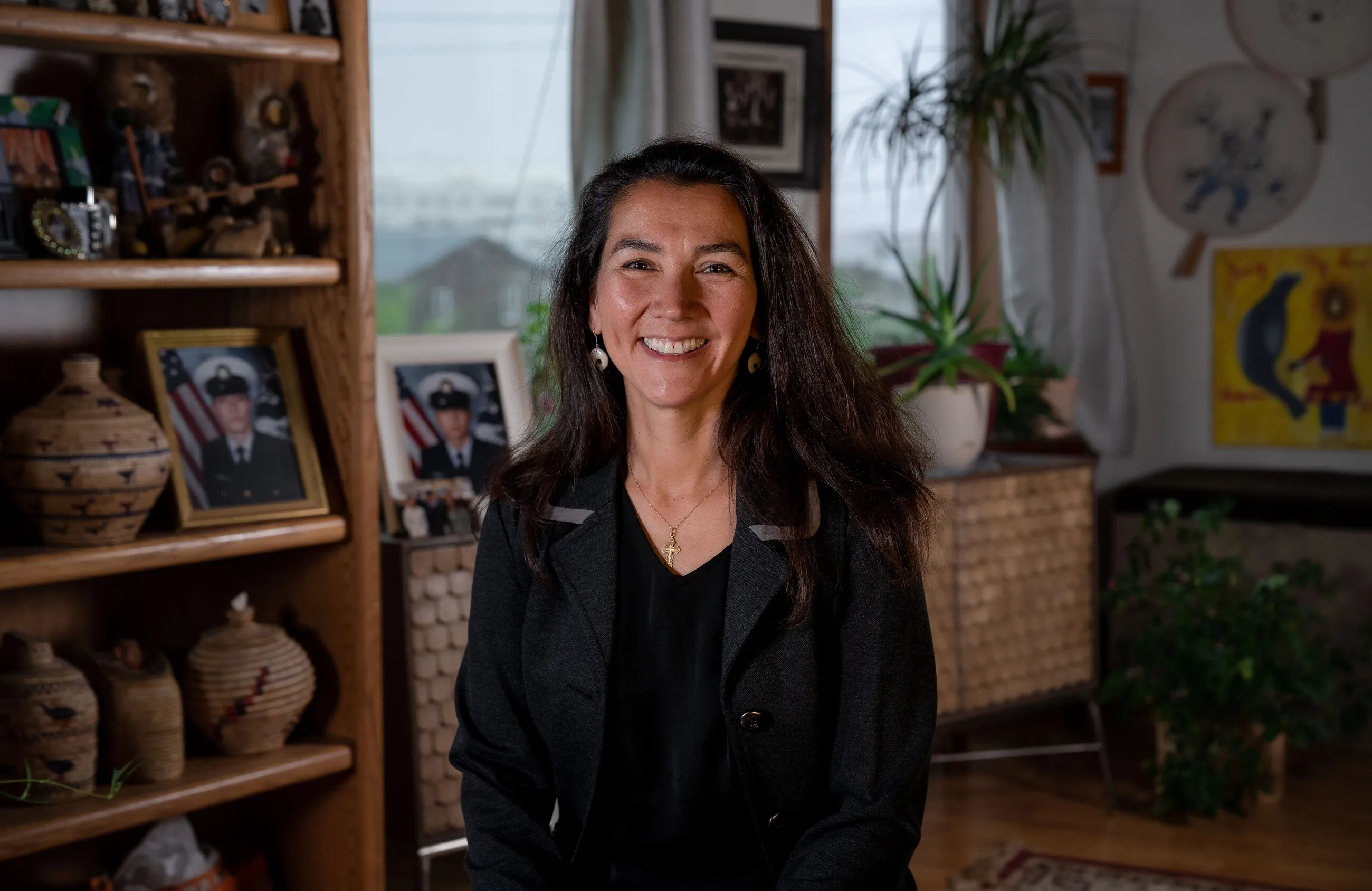 Mary Peltola at home in Bethel, smiling among family photographs and woven baskets.