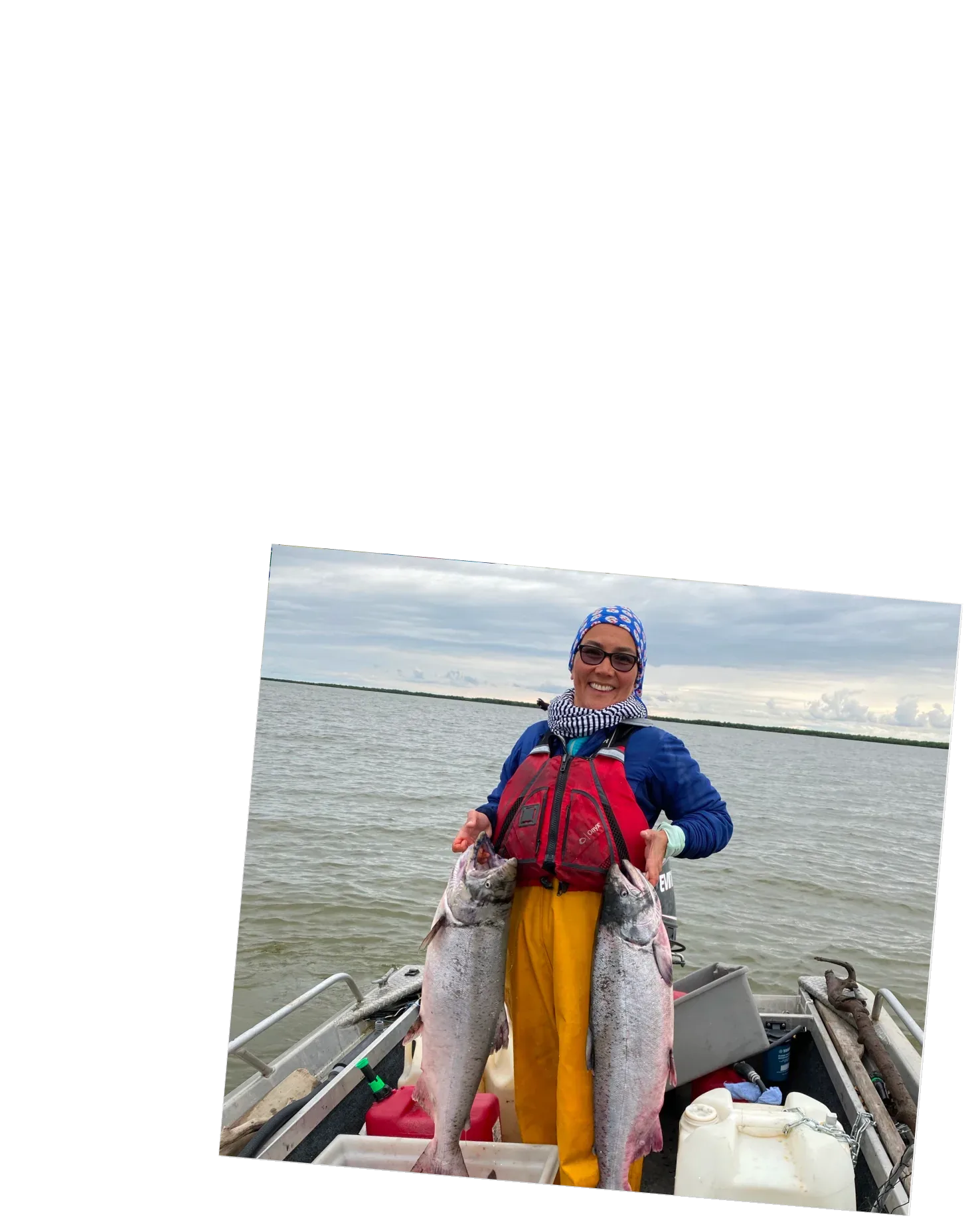 Mary Peltola holding two salmon in her skiff.