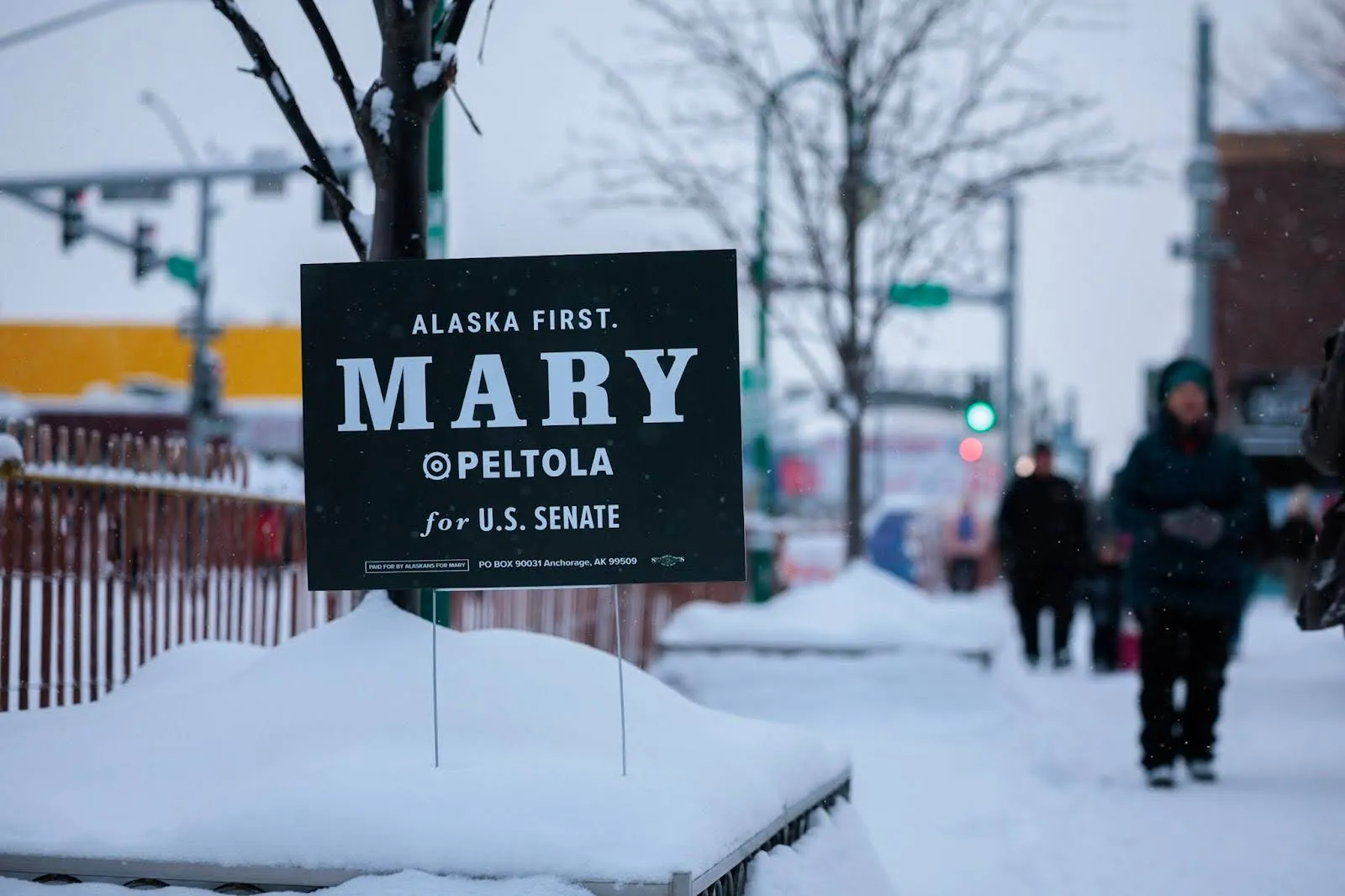 An “Alaska First. Mary Peltola for U.S. Senate” yard sign in the snow on a city street.