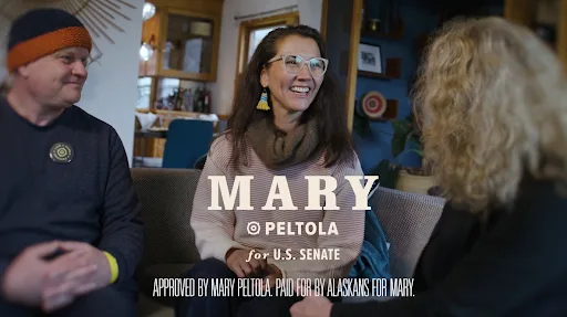 A frame from the ad “For Alaska”: Mary Peltola laughing with Alaskans in a living room, under the Mary Peltola for U.S. Senate logo.