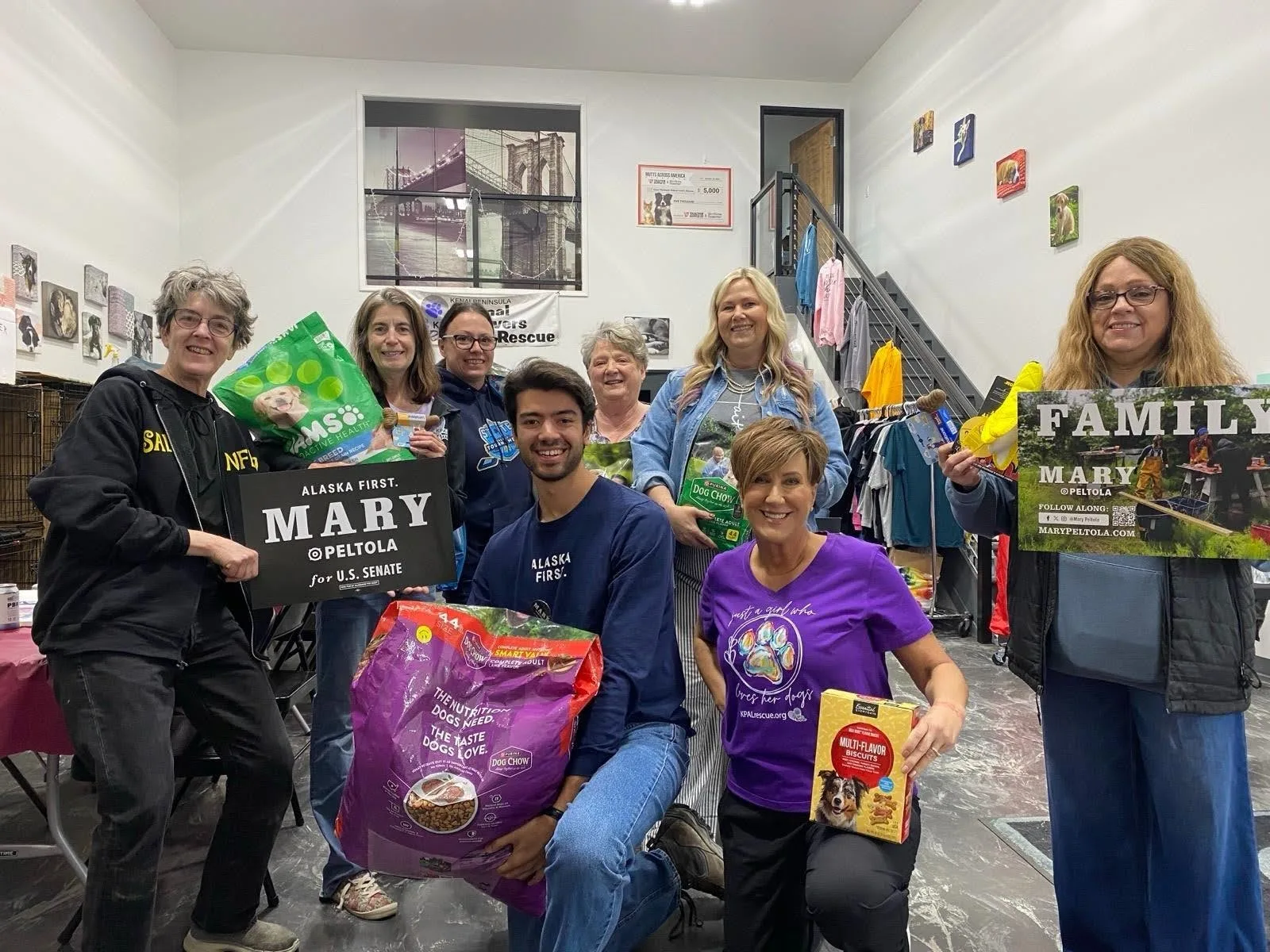 Volunteers with donated pet food and Mary signs at an animal shelter.
